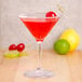 A GET SAN Plastic Martini Glass with a drink, a lemon twist, and a cherry on a table.