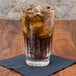 A Libbey Winchester highball glass filled with soda and ice on a napkin.