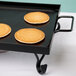 An American Metalcraft wrought iron griddle with four pancakes on it.