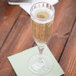 A GET SAN plastic fluted champagne glass of champagne on a table.