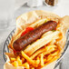 A Tofurky Italian sausage with french fries and ketchup in a basket.