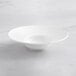 An Acopa Cordelia white porcelain bowl with a wide rim and a curved edge on a marble surface.