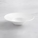 An Acopa Cordelia white porcelain bowl with a wide, curved rim on a marble surface.