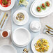 A table set with Acopa Cordelia white porcelain platters and utensils.