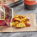 A bag of Snyder's of Hanover Honey Mustard & Onion Pretzel Pieces on a table with a napkin.