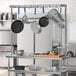 A kitchen with pots and pans hanging from a Regency stainless steel table-mounted pot rack.