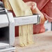 A woman using an Imperia pasta machine to make noodles on a counter.
