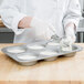 A person in a white coat making jumbo muffins in a Chicago Metallic mini cake and jumbo muffin pan.