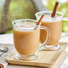 A glass mug of David Rio Orca Spice Sugar-Free Chai Tea Latte with a cinnamon stick in it.
