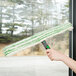 A hand holding a grey and green Unger Monsoon Plus window cleaner sleeve.