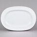 An Arcoroc white oval porcelain platter with a rim on a gray surface.