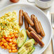 A plate of breakfast food including Field Roast plant-based apple maple sausage links, eggs, and avocado.