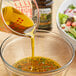 A bowl of salad with Colavita olive oil being poured into it.