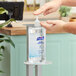 A person using a Purell hand sanitizer pump on a table.