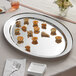 An Acopa stainless steel oval platter with food on it.