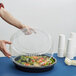 A person holding a WNA Comet clear plastic lid over a food container.