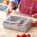 A person holding an Enjay marble laminated box of strawberries.