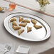 An Acopa stainless steel oval platter with food on it.