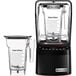 A black Blendtec commercial blender with clear containers on the side.