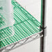 A metal shelf with green plastic mesh liner on it.