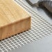 A wooden block on a white mesh surface.
