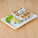 A Thunder Group Blue Bamboo rectangular melamine BBQ plate with sushi on it.