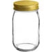 A clear glass Acopa Mason candle jar with a gold lid.