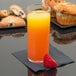 A Libbey straight sided glass of orange juice next to a strawberry and muffins.