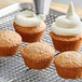 A group of Gold Medal spice cupcakes with white frosting on a metal rack.