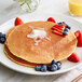A plate of Gold Medal pancakes topped with strawberries and blueberries.