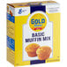 A box of Gold Medal Basic Muffin Mix on a white surface with two muffins.