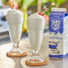 Two Island Oasis yogurt milkshakes in white cups next to a carton of yogurt.