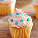 A cupcake with blue and white snowflake sprinkles on white frosting.