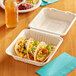 An EcoChoice bagasse take-out container with three tacos on a table.