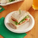 A sandwich on an EcoChoice natural bagasse blend plate with a drink.