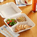 A EcoChoice natural bagasse 3-compartment take-out container with chicken and salad.