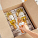 A hand opening a Lavex Molded Fiber wine bottle shipper box to reveal a bottle of wine inside.