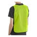 A person wearing a lime high visibility safety vest with a back view.