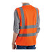 A person wearing a Lavex orange safety vest with reflective stripes.