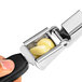A hand using an OXO Good Grips garlic press to press garlic.