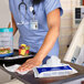 A nurse using Purell Surface Disinfecting Wipes to clean a table in a hospital cafeteria.