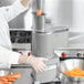 A chef using a Waring commercial food processor to shred carrots.