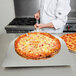 An American Metalcraft aluminum pizza peel with a pizza on it being held by a chef.