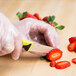 A person using a yellow Mercer Culinary Millennia paring knife to cut a strawberry.