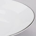 A white porcelain soup bowl with a silver rim.