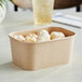 A rectangular Kraft paper take-out container filled with doughnuts.