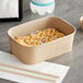 A rectangular Kraft paper take-out container with sushi inside.