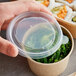 A hand holding a Choice plastic lid over a container of food.