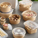 A rectangular Kraft paper take-out container filled with food and a clear plastic lid.