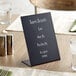 A black Choice tabletop chalkboard sign with white writing on a brown surface.